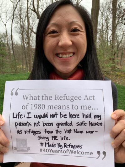 Quyen holds a sign about owing her life to the Refugee Act of 1980