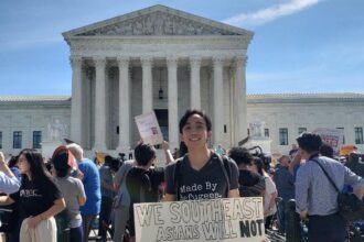 A young person standing on the steps of the Supreme Court building