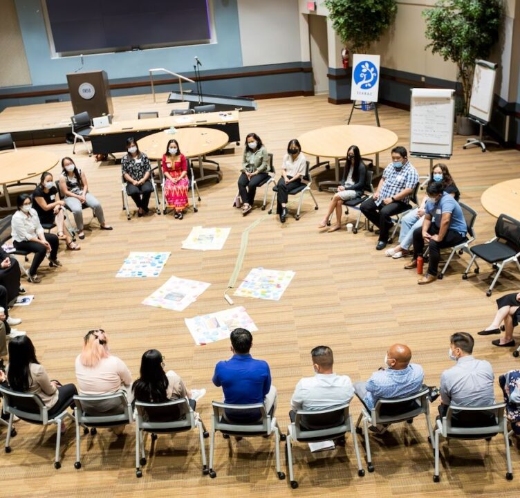 People sit in a circle inside a conference room