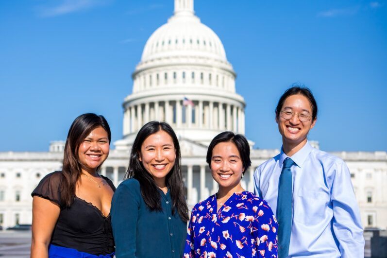 Four people pose in front of the Capitol