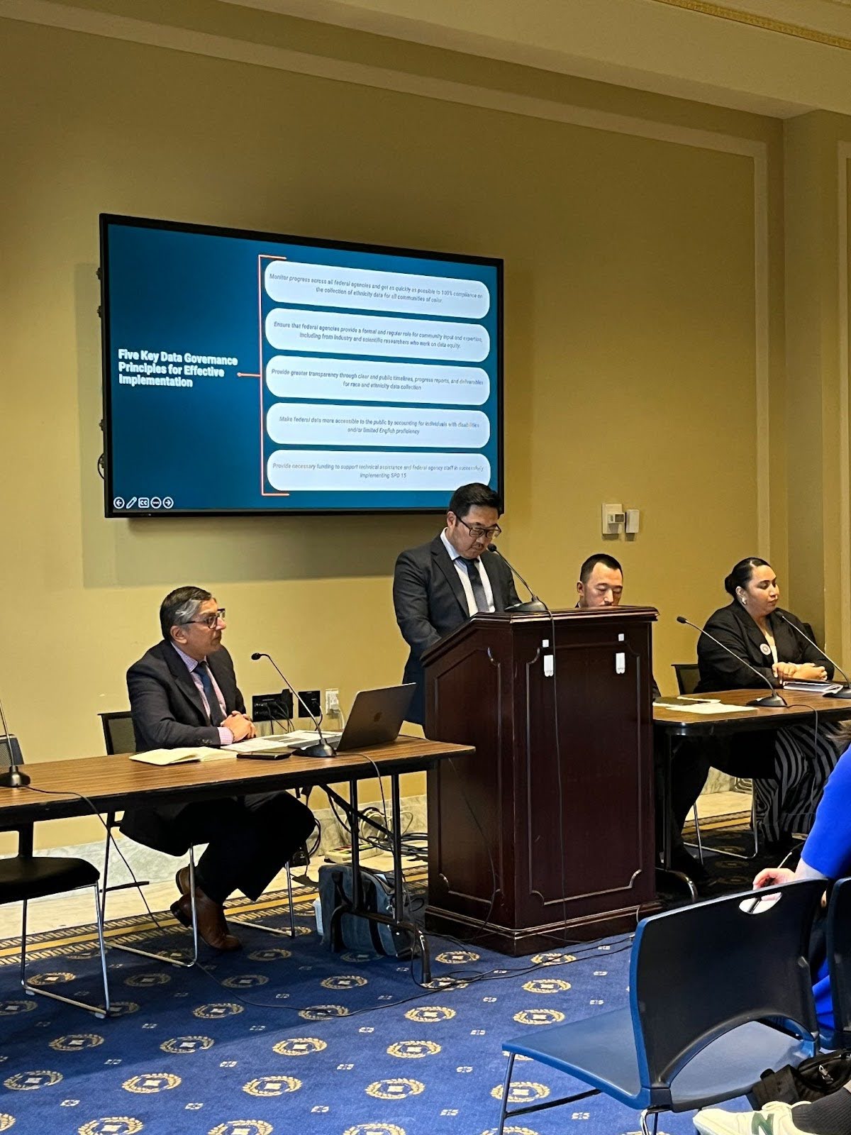 A person wearing a black suit giving a presentation on the data equity