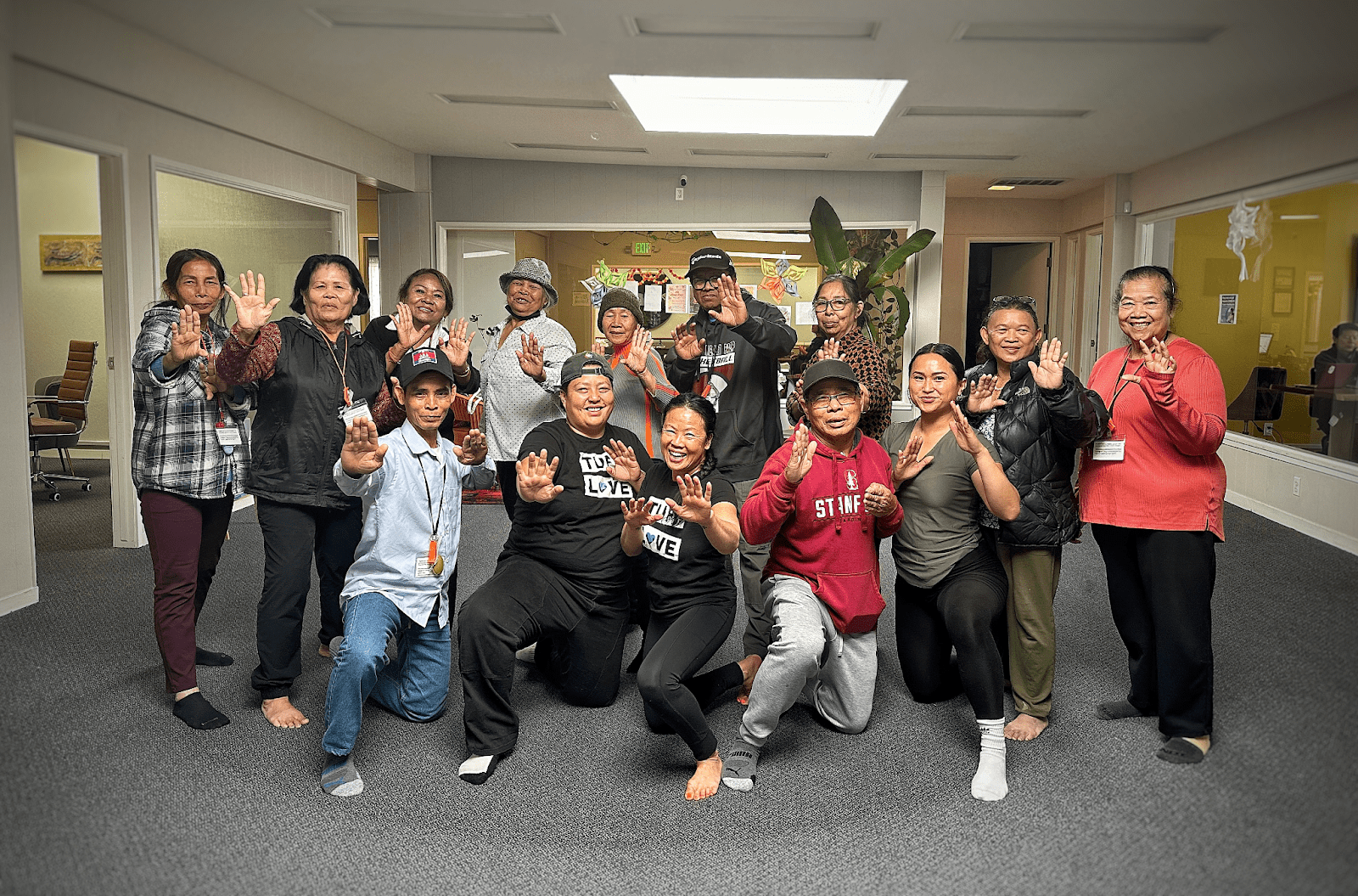 A group of elders and young people smiling together with defense poses to show their strength and new self defense skills. 