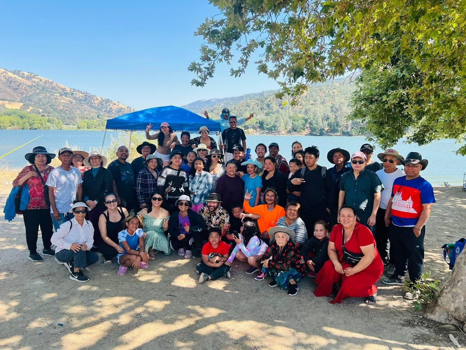 A group of people smiling together with a beautiful lake behind them. 