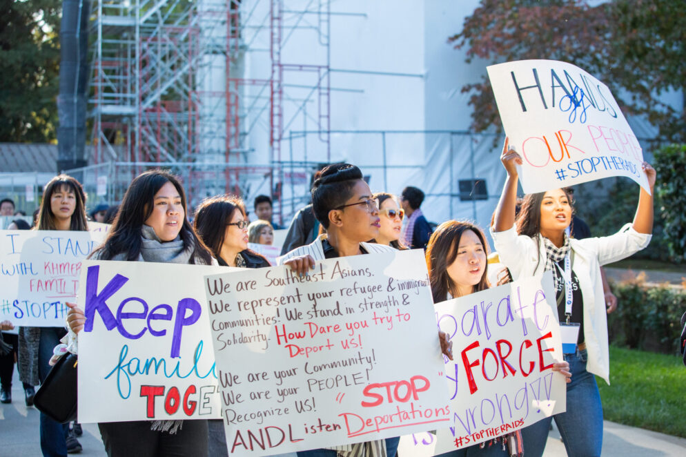 Individuals holding anti-deportation signs at a rally