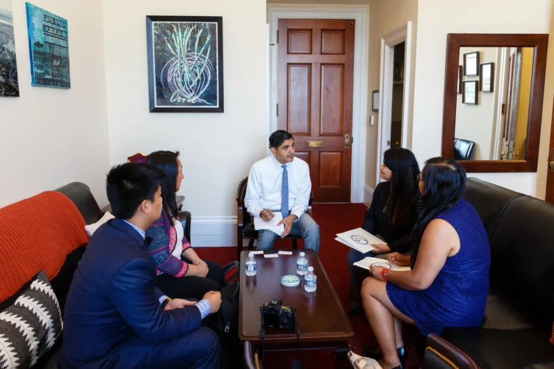 group of individuals sit around a coffee table in discussion in an office