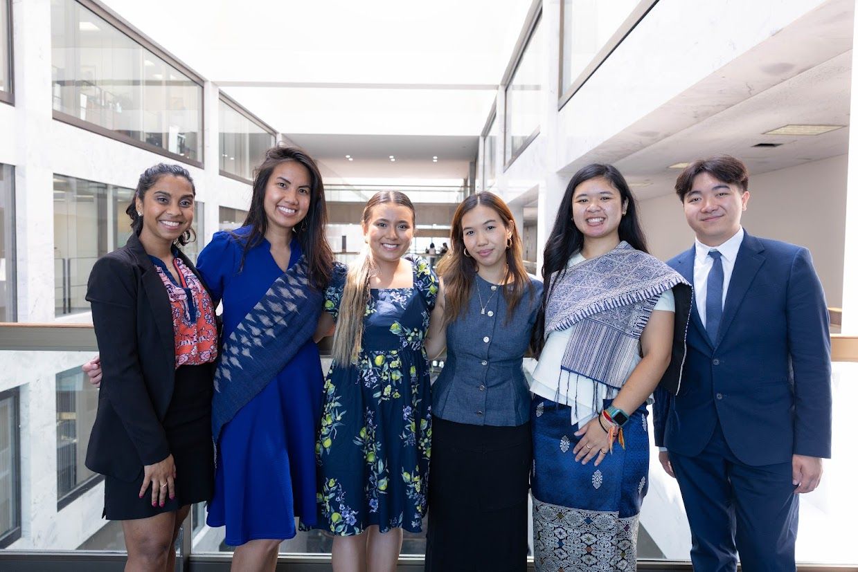 6 individuals in shades of blue business attire and cultural attire pose